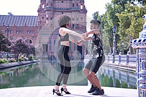 Multi-ethnic young couple doing figures while dancing bachata sensually outdoors