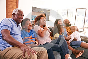 Multi-Generation African American Family Relaxing At Home Sitting On Sofa Watching TV Together