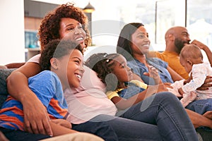 Multi-Generation African American Family Relaxing At Home Sitting On Sofa Watching TV Together