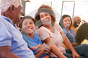 Multi-Generation African American Family Relaxing At Home Sitting On Sofa Watching TV Together