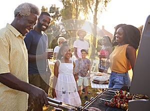 Multi generation black family barbecue, grandad grilling photo