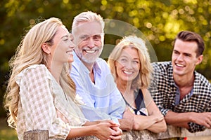 Multi-Generation Family With Adult Offspring Leaning On Fence Walking In Countryside