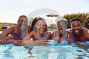 Multi-Generation Family With Adult Offspring On Summer Holiday On Inflatable In Swimming Pool