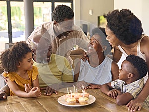 Multi-Generation Family Celebrate Grandmother\'s Birthday With Cake And Candles Around Table At Home