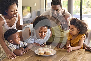 Multi-Generation Family Celebrate Grandmother's Birthday With Cake And Candles Around Table At Home 