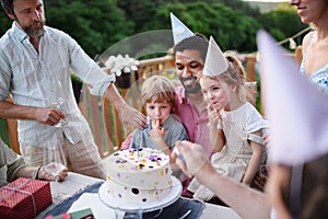 Multi generation family celebrating birthday and have garden party outside in the backyard on patio.