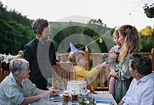 Multi generation family celebrating birthday and have garden party outside in the backyard on patio.