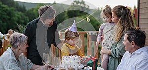 Multi generation family celebrating birthday and have garden party outside in the backyard on patio.