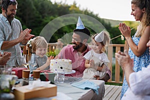 Multi generation family celebrating birthday and have garden party outside in the backyard on patio.