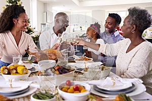 Multi-Generation Family Celebrating Christmas At Home Eating Meal And Making Toast With Wine