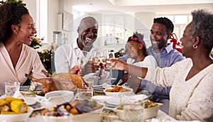 Multi-Generation Family Celebrating Christmas At Home Eating Meal And Making Toast With Wine