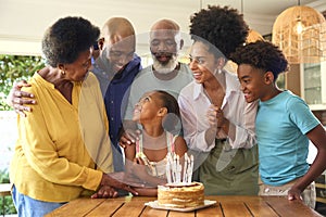 Multi-Generation Family Celebrating Granddaughter\'s Birthday With Cake And Candles At Home