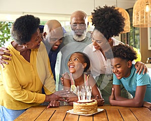 Multi-Generation Family Celebrating Granddaughter\'s Birthday With Cake And Candles At Home