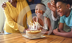 Multi-Generation Family Celebrating Granddaughter\'s Birthday With Cake And Candles At Home