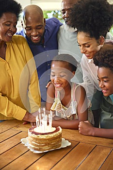 Multi-Generation Family Celebrating Granddaughter\'s Birthday With Cake And Candles At Home