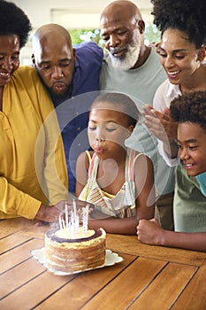 Multi-Generation Family Celebrating Granddaughter\'s Birthday With Cake And Candles At Home