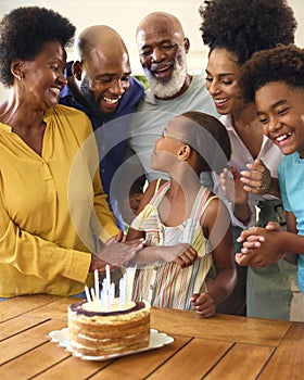 Multi-Generation Family Celebrating Granddaughter's Birthday With Cake And Candles At Home