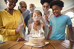 Multi-Generation Family Celebrating Granddaughter\'s Birthday With Cake And Candles At Home