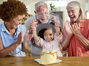 Multi-Generation Family Celebrating Granddaughter\'s Birthday At Home With Cake