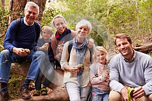 Multi-generation family eating in a forest, portrait