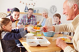 Multi Generation Family Eating Lunch At Kitchen Table