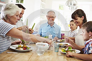 Multi Generation Family Eating Meal Around Kitchen Table