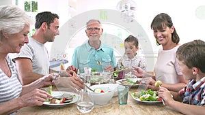 Multi Generation Family Eating Meal Around Kitchen Table