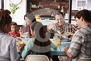 Multi Generation Family Enjoying Meal Around Table At Home Together