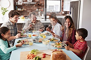 Multi Generation Family Enjoying Meal Around Table At Home Together