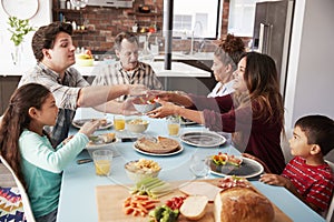 Multi Generation Family Enjoying Meal Around Table At Home Together