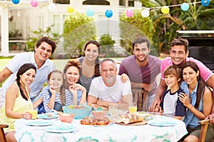 Multi Generation Family Enjoying Meal In Garden Together