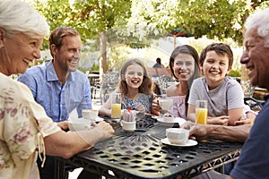 Multi Generation Family Enjoying Snack At Outdoor Cafï¿½ Together