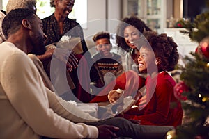 Multi-Generation Family Exchanging And Opening Gifts Around Christmas Tree At Home