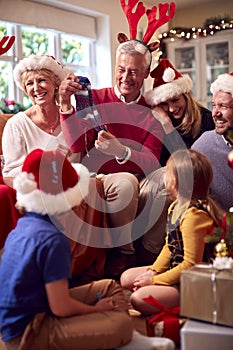 Multi-Generation Family Exchanging And Opening Gifts Around Christmas Tree At Home