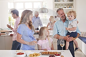 Multi-Generation Family And Friends Gathering In Kitchen For Celebration Party photo