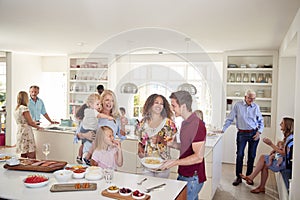 Multi-Generation Family And Friends Gathering In Kitchen For Celebration Party photo
