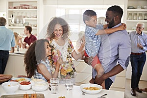 Multi-Generation Family And Friends Gathering In Kitchen For Celebration Party photo