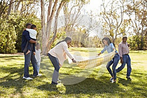 Multi Generation Family Going On Picnic In Park Together