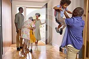 Multi-Generation Family With Grandparents Greeting Grandchildren in Hallway At Home