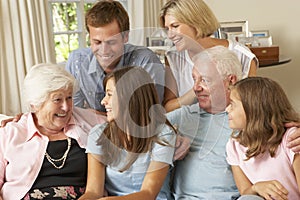 Multi Generation Family Group Sitting On Sofa Indoors