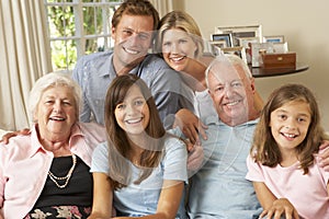 Multi Generation Family Group Sitting On Sofa Indoors