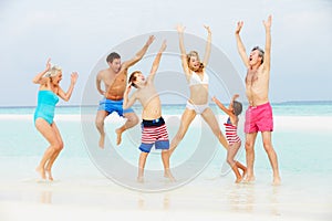 Multi Generation Family Having Fun In Sea On Beach Holiday