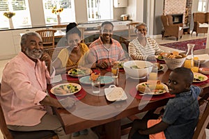 Multi-generation family having meal together on dining table at home