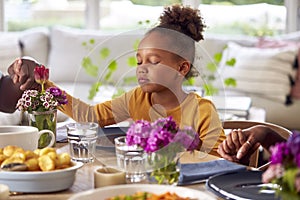 Multi Generation Family Holding Hands Around Table At Home Saying Grace Before Eating Meal Together