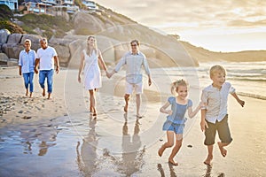 Multi generation family holding hands and walking along the beach together. Caucasian family with two children, two