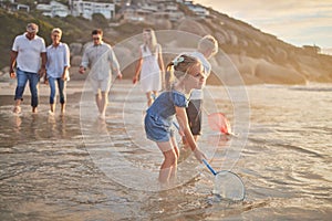 Multi generation family holding hands and walking along the beach together. Caucasian family with two children, two