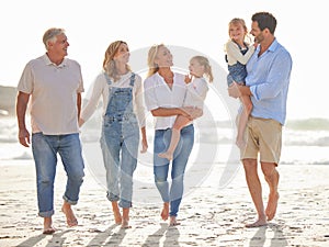 Multi generation family holding hands and walking along the beach together. Caucasian family with two children, two
