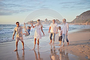 Multi generation family holding hands and walking along the beach together. Caucasian family with two children, two