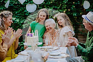 Multi-generation family on outdoor summer garden party, celebrating birthday