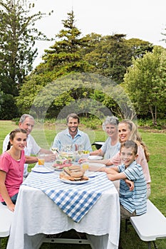 Multi generation family at picnic table having dinner outside